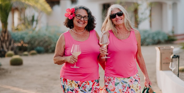Two women enjoying a glass of wine in their ripskirts and matching pink tank tops.